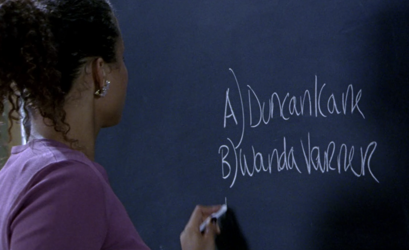 Screenshot of S1E6 of Veronica Mars. Ms. Dent, facing away from the viewer, is writing on a blackboard in chalk. The blackboard says "A) Duncan Kane" and on the next line "B) Wanda Varner."