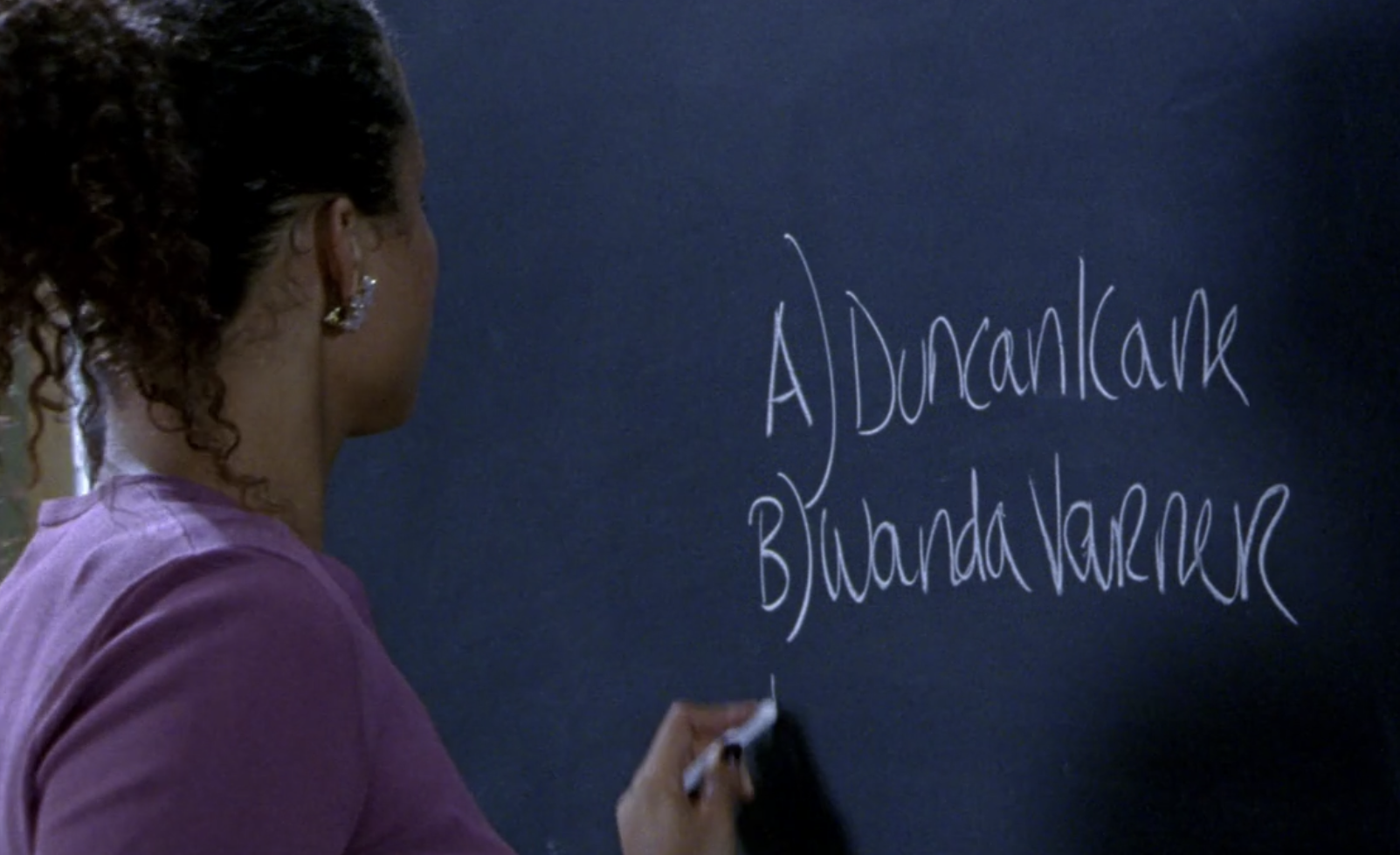 Screenshot of S1E6 of Veronica Mars. Ms. Dent, facing away from the viewer, is writing on a blackboard in chalk. The blackboard says "A) Duncan Kane" and on the next line "B) Wanda Varner." 