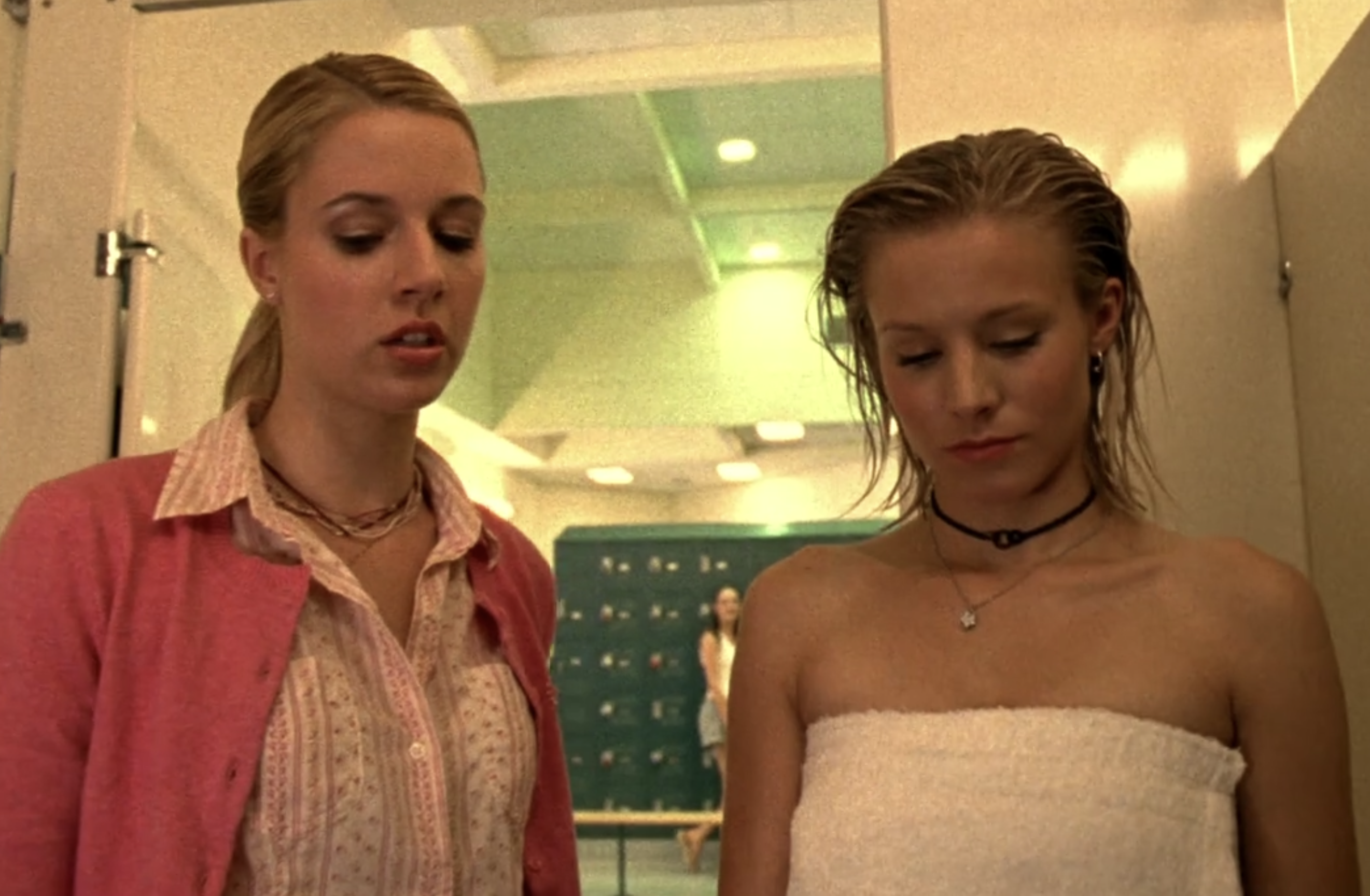 A screenshot from Veronica Mars S1E8, Meg and Veronica are standing in the locking room looking down at the (off-screen) toilet where Veronica's clothes have been stuffed. Veronica is wearing a towel.