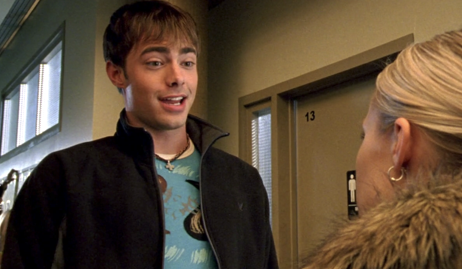 Screenshot from S1E9 of Veronica Mars. Casey Gant is looking at Veronica. They are standing in the school hallway and Casey's eyebrows are raised and he's in the middle of talking with a smile on his face.