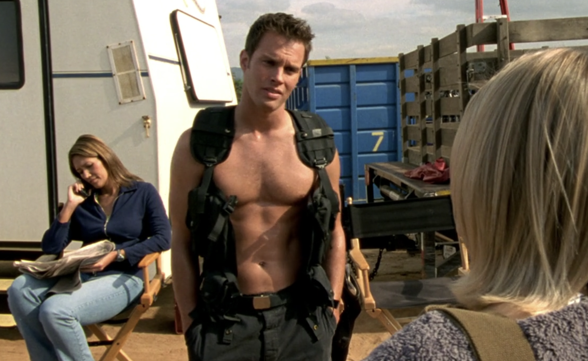 Screenshot from Veronica Mars season one, episode 10. Connor is shirtless and wearing a black tactical vest. He's on a movie set looking at Veronica who faces away from the camera.