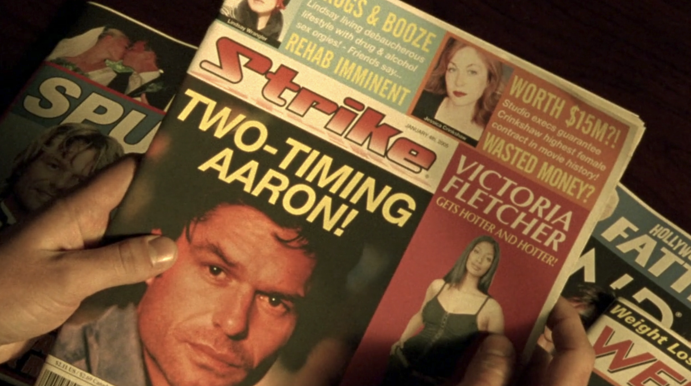 Screenshot from S1E12 of Veronica Mars. It's a shot of a pair of hands holding a tabloid called "Strike." There's a picture of Aaron Echolls with the headline "Two-Timing Aaron"