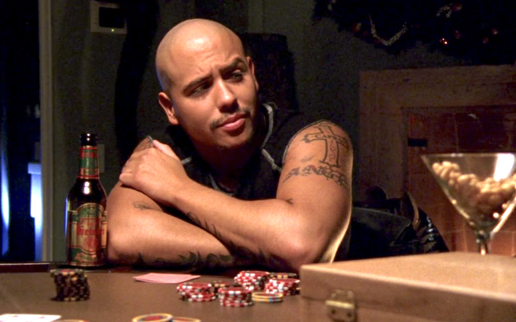 Screenshot from Veronica Mars season one, episode 10. Weevil is sitting at the poker table, his arms folded, looking with disdain at someone next to him at the table who is off-screen.