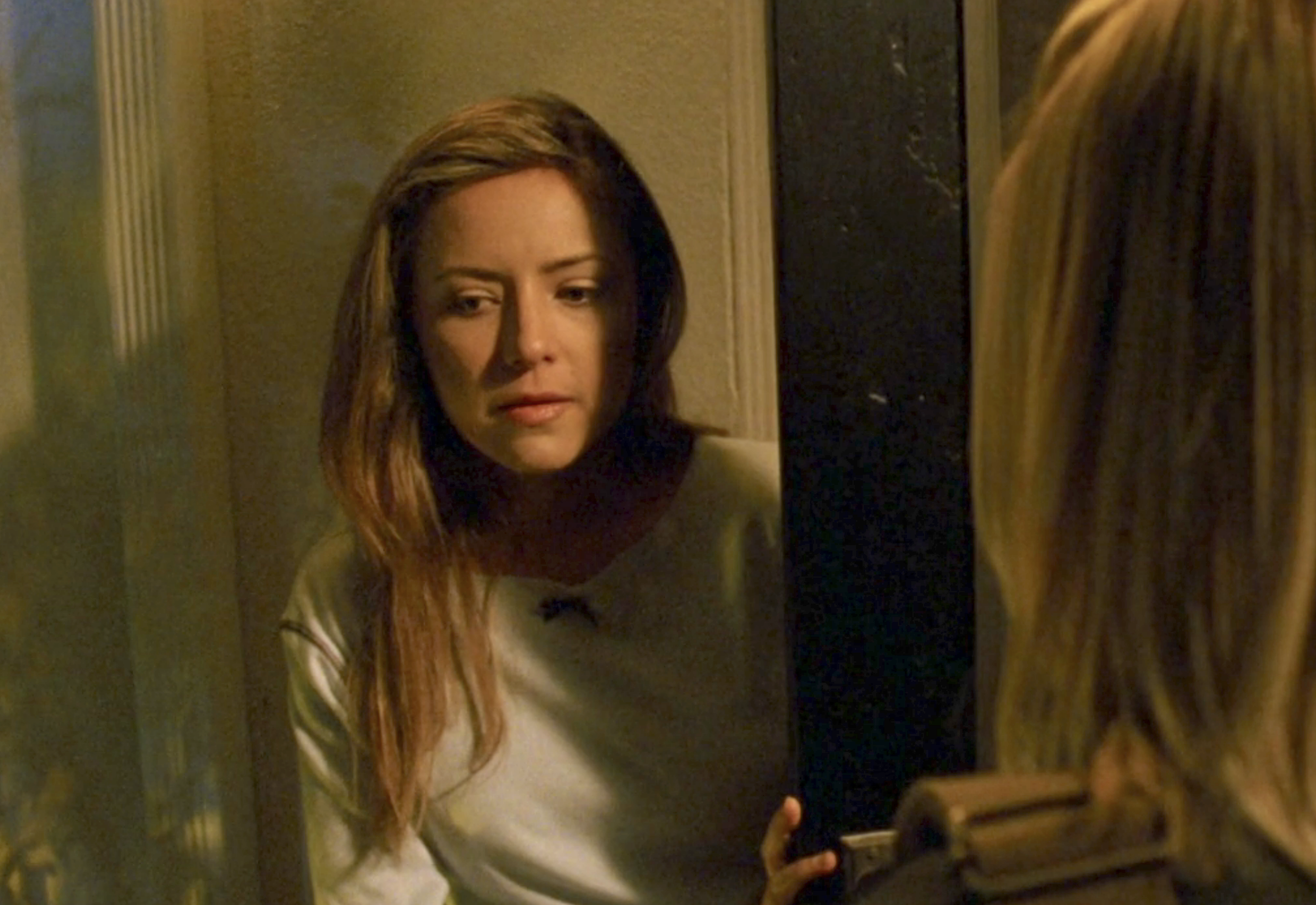 Screenshot from S1E14 of Veronica Mars. A young woman with long blond hair is standing in a front door talking to Veronica, whose back is to us.