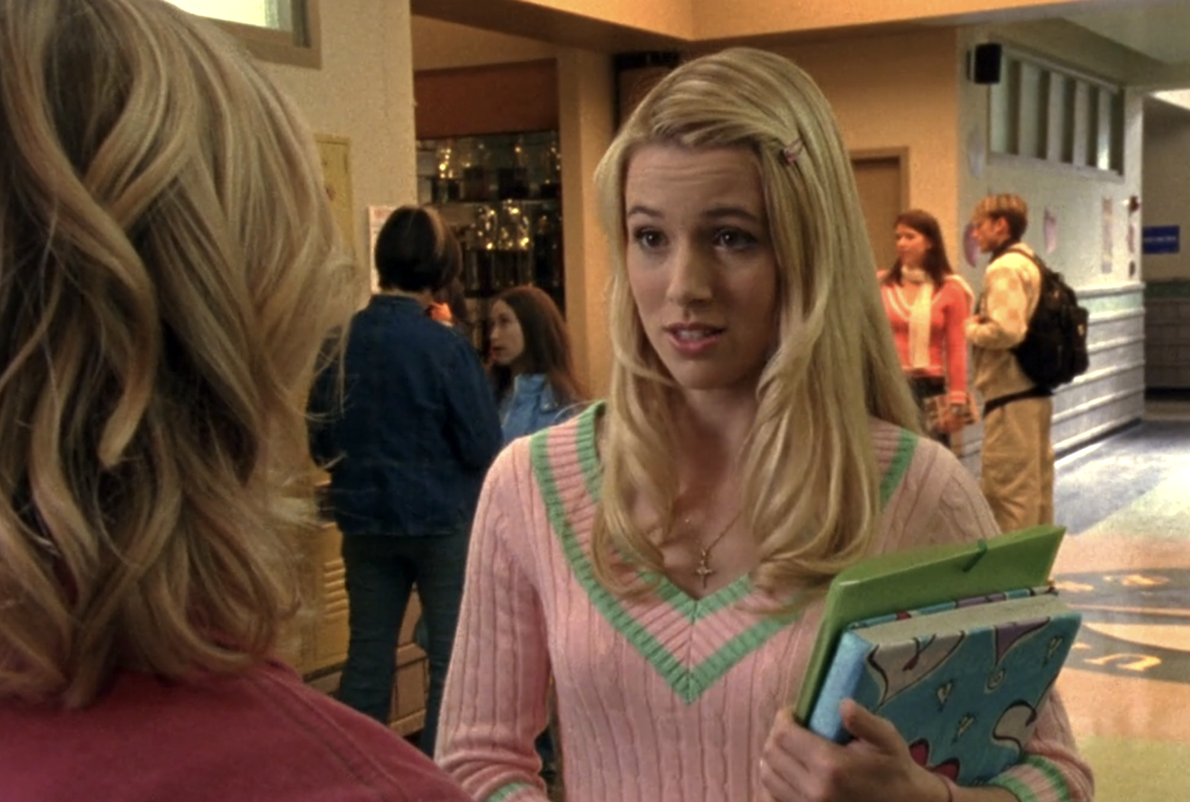 Screenshot from Veronica Mars S1E15. Meg in a pink sweater with green stripes is looking incredulously at Veronica.