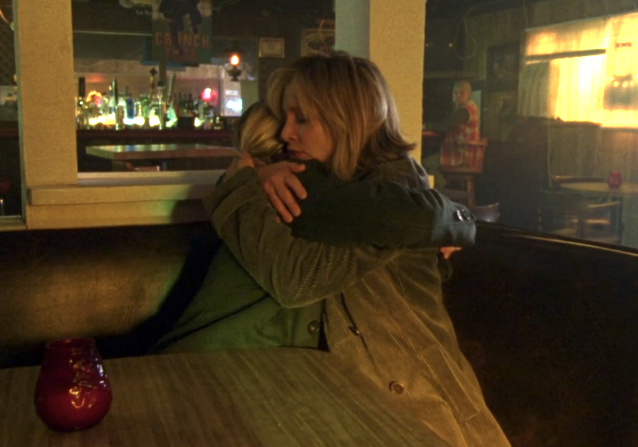 Screenshot from S1E16 of Veronica Mars. Veronica and her mom are at a bar sitting in a booth and hugging.
