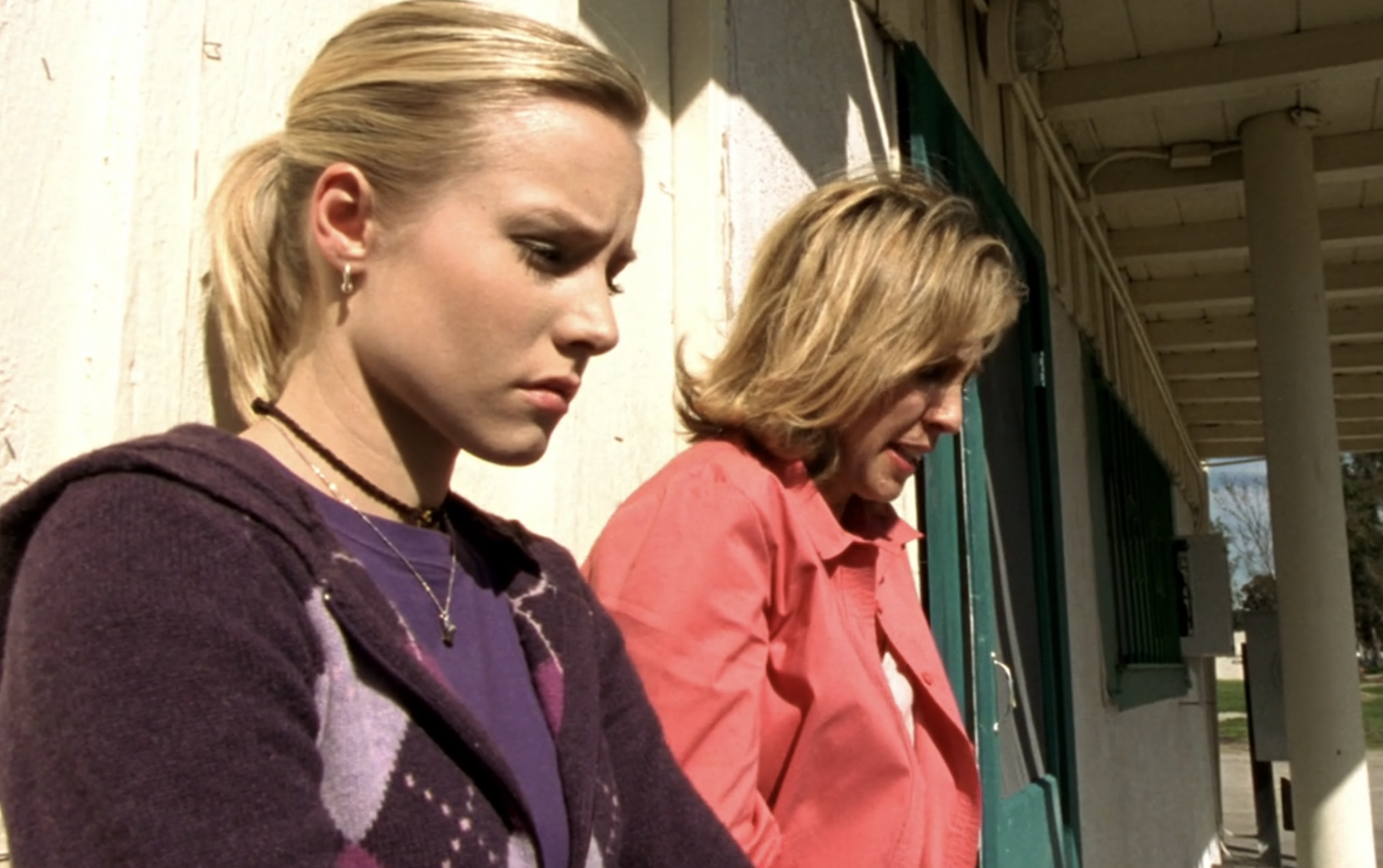 Screenshot from S1E16 of Veronica Mars. Veronica and Lianne are outside in daytime, both leaning on a building. Both are looking down. Veronica has an expression of concern.