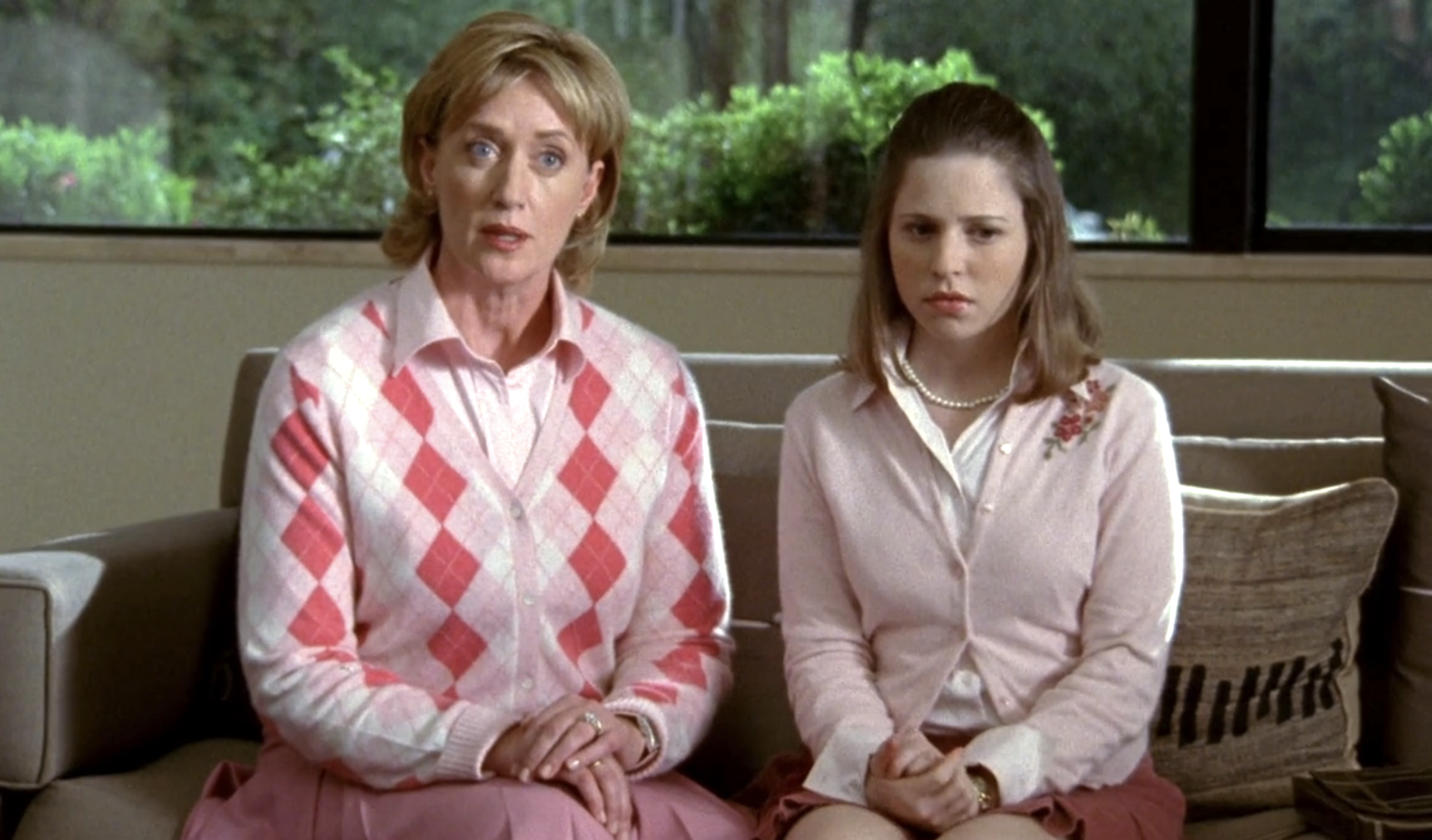 Screenshot from S1E17 of Veronica Mars. Mrs. Fuller and her daugher Sabrina are both dressed conservatively and preppily, hands folded in their laps, sitting beside each other
