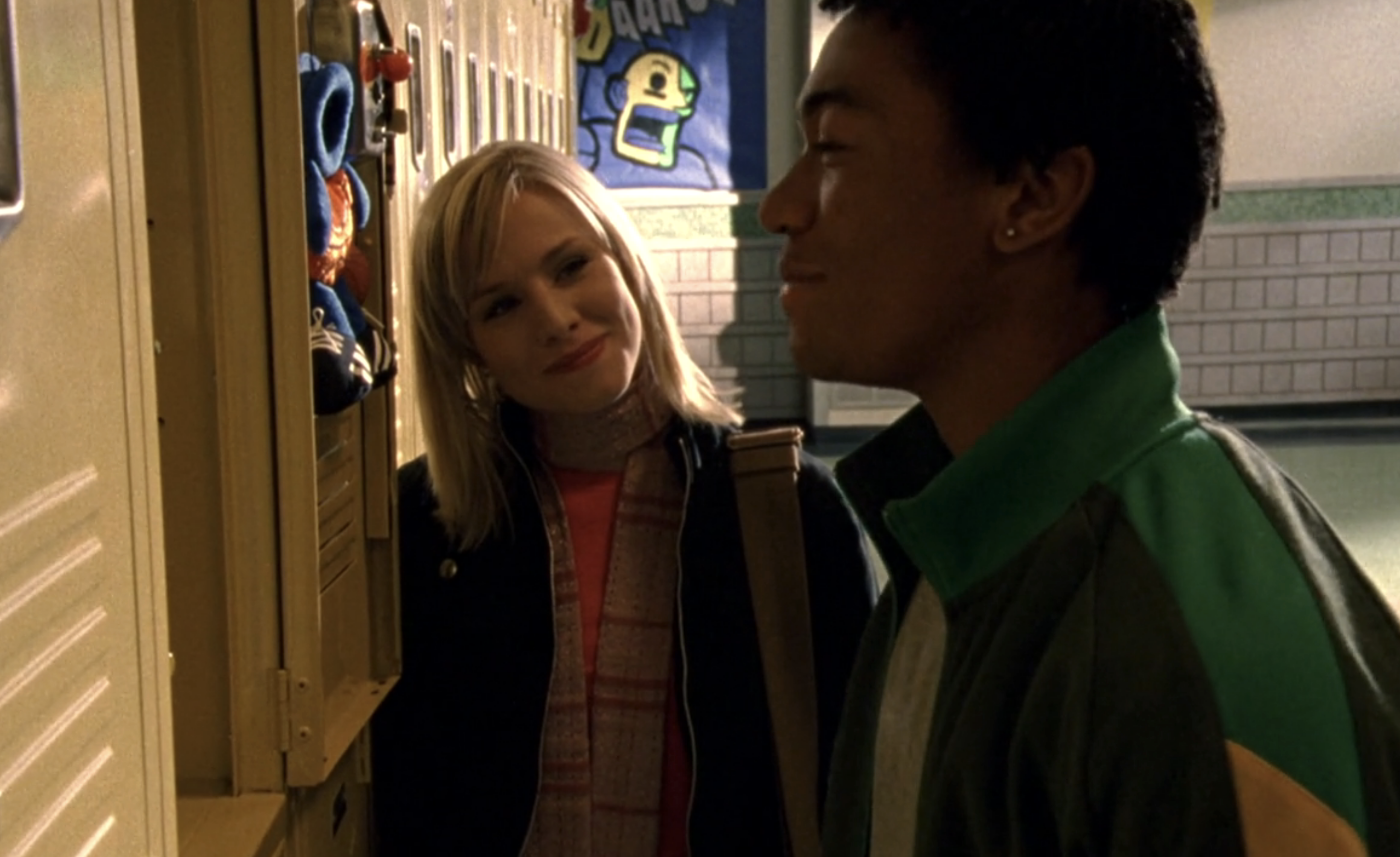 Screenshot from Veronica Mars S1E18. Veronica and Wallace standing at the lockers. Veronica is looking at Wallace and smiling. Wallace is facing the lockers and smirking