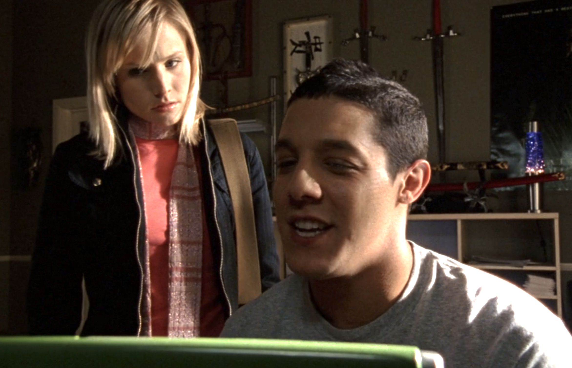 Screenshot from Veronica Mars S1E18. Norris is sitting at a computer looking at the screen. Veronica is standing behind him looking at the screen.