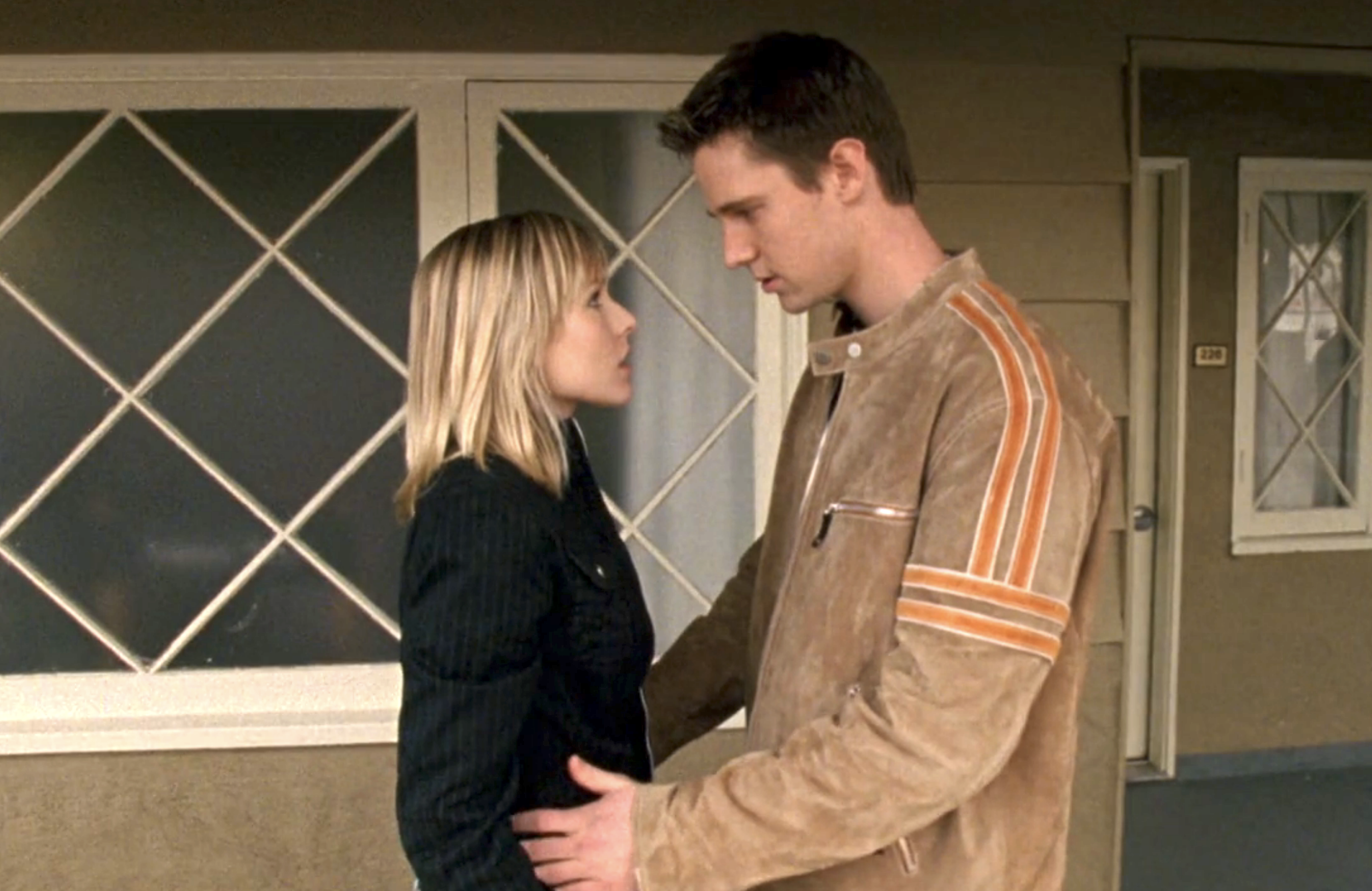 Screenshot from S1E18 of Veronica Mars. Veronica and Logan are standing on a hotel balcony looking into each other's eyes. Logan's hands are on Veronica's waist.