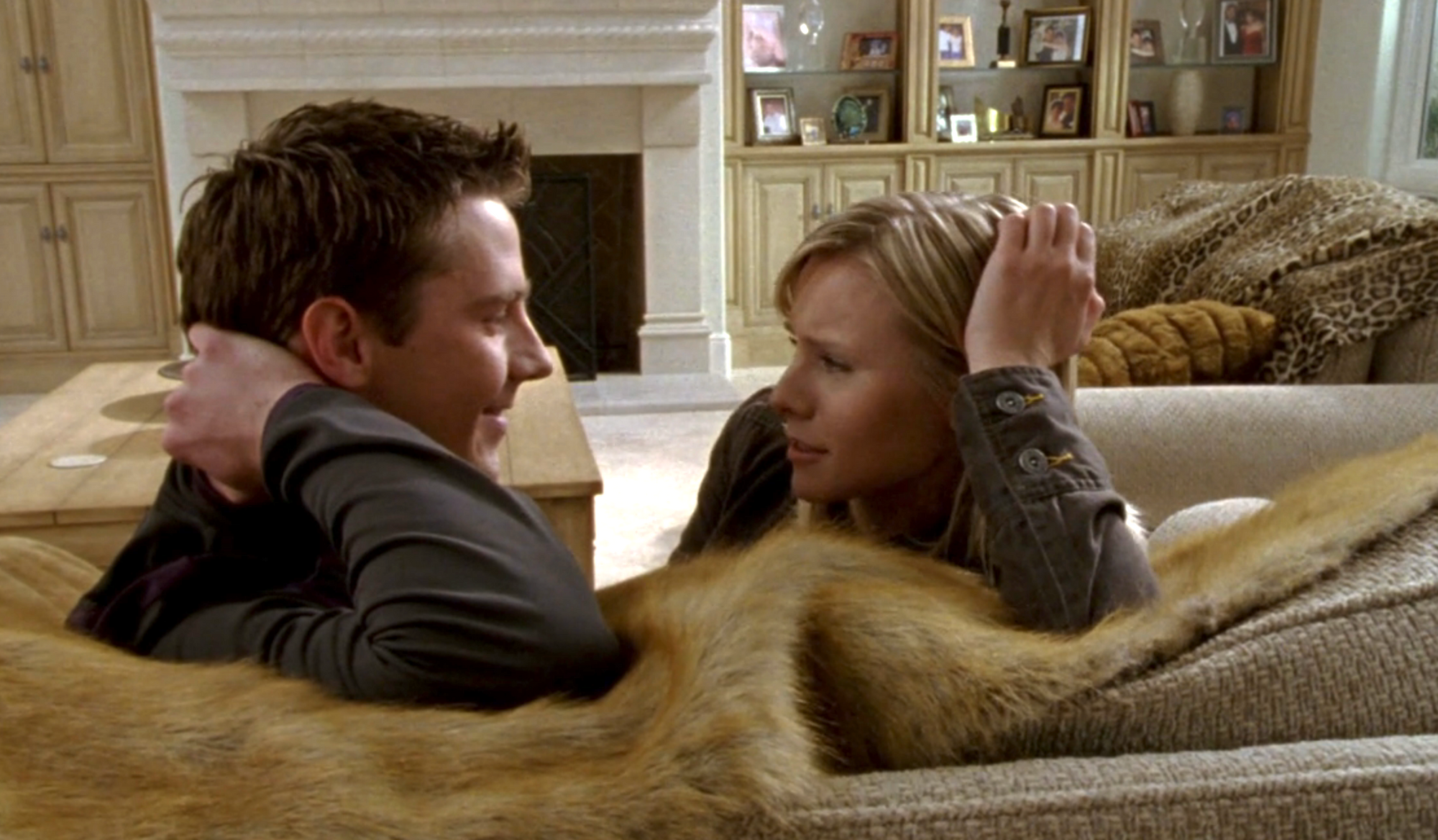 Screenshot from S1E20 of Veronica Mars. Logan and Veronic are sitting on the couch looking at each other. Logan has his right elbow on the couch and Veronica has her left elbow on the couch. They're each leaning on their hands.